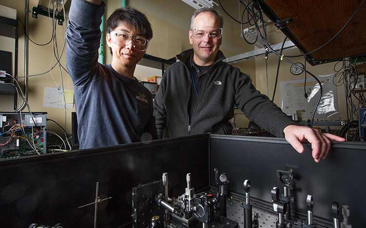 Photo of two male scientists in a laboratory with their hands on some scientific equipment.