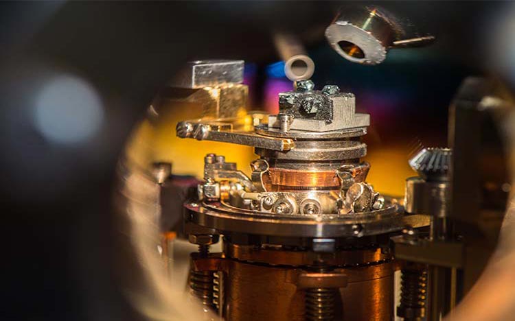 Photo of laboratory analytical tool showing a sample in a metallic holder and two apertures above the sample.