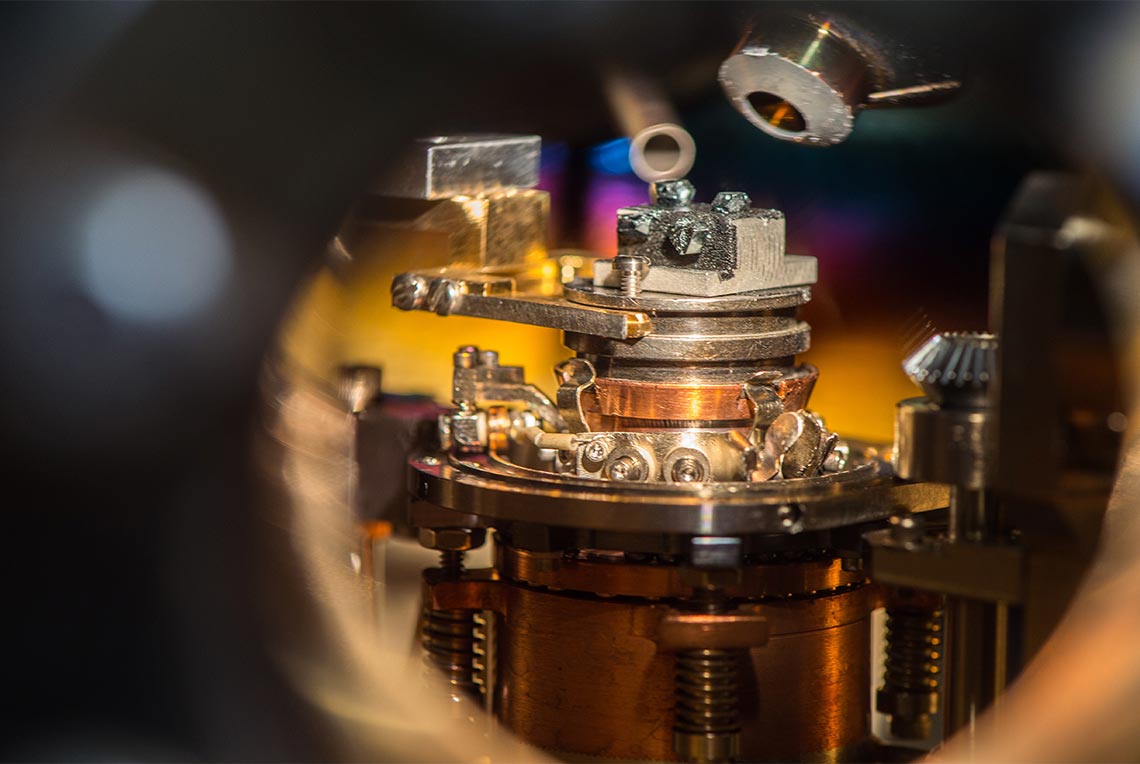 Photo of laboratory analytical tool showing a sample in a metallic holder and two apertures above the sample.